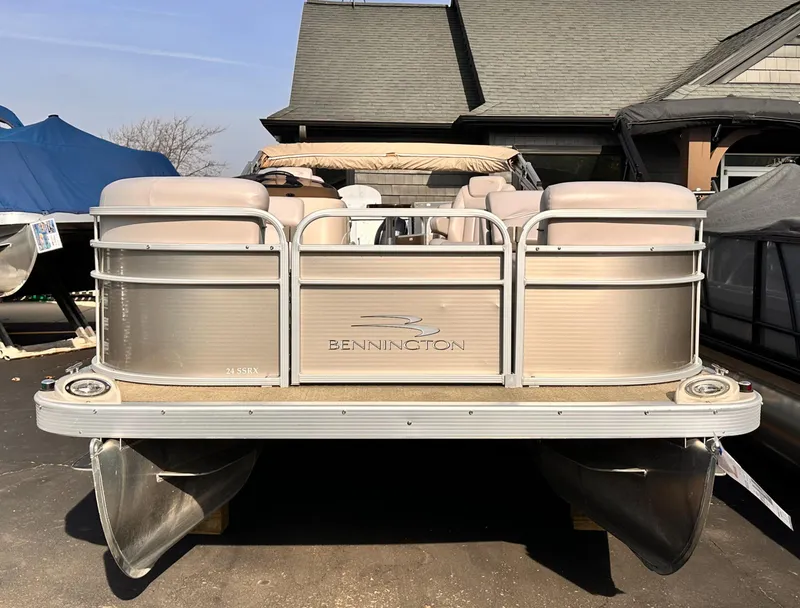 Slide: The Image of 2015 Bennington S24 pontoon boat with beige seating, docked near a house. - 3