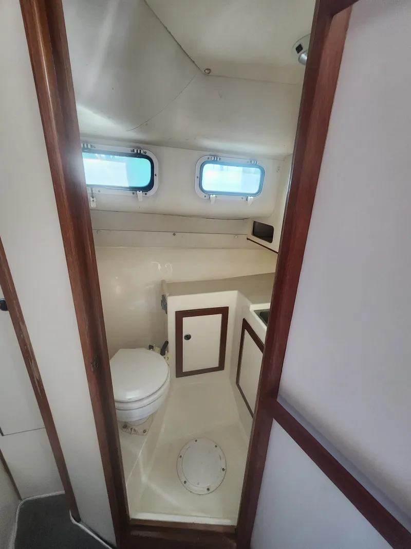 Slide: The Image of Interior view of a boat bathroom with toilet, sink, and porthole windows. - 16