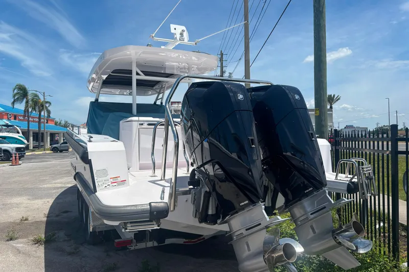 Slide: The Image of 2024 Axopar 37 Sun-Top boat with dual outboard engines, parked outdoors. - 12