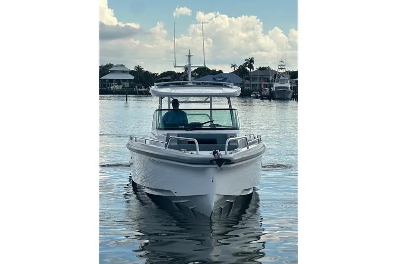Slide: The Image of 2024 Axopar 37 Sun-Top boat cruising on calm water, front view. - 3
