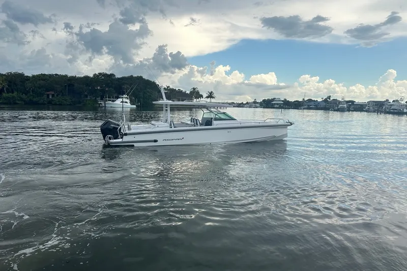 Slide: The Image of 2024 Axopar 37 Sun-Top boat cruising on a calm lake under a cloudy sky. - 2