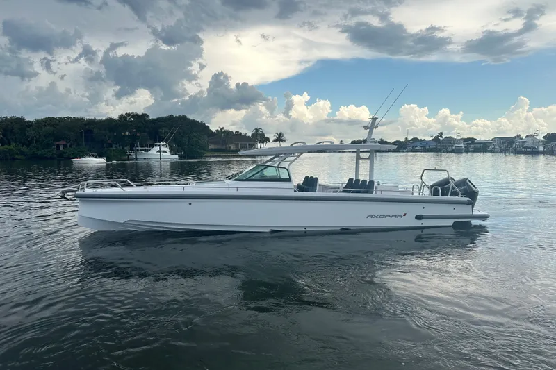 The Image of 2024 Axopar 37 Sun-Top boat on calm water under a cloudy sky. - 0