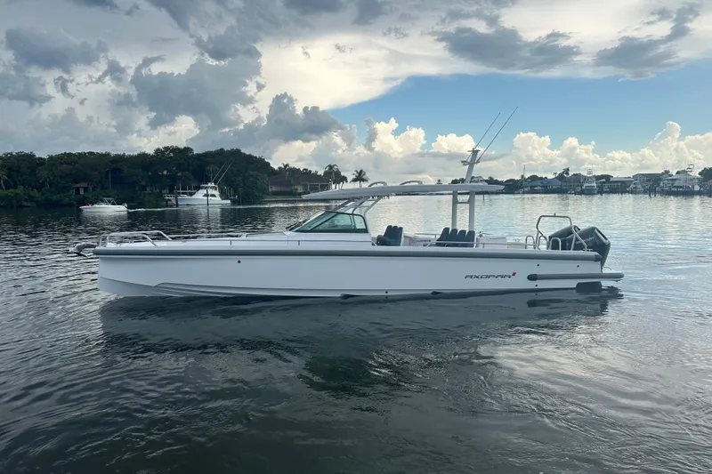 Slide: The Image of 2024 Axopar 37 Sun-Top boat on calm water under cloudy sky. - 1