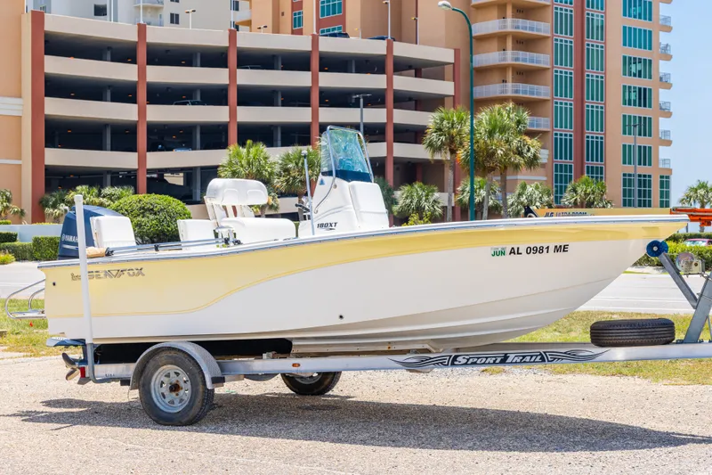 The Image of 2012 Sea Fox 180 Viper boat on trailer, parked near modern buildings and palm trees. - 0