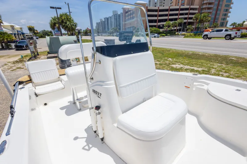 Slide: The Image of 2012 Sea Fox 180 Viper boat interior with white seating and console, parked near a road. - 27