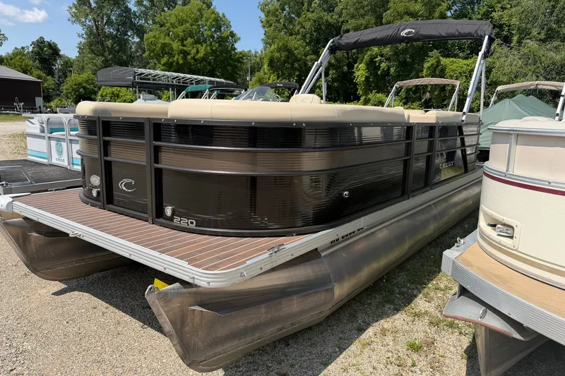 Slide: The Image of 2019 Crest II 230 SL pontoon boat with sleek black design, docked outdoors. - 2