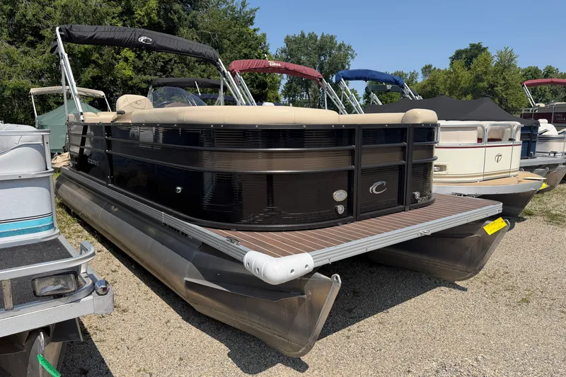 Slide: The Image of 2019 Crest II 230 SL pontoon boat with black exterior, parked on gravel lot. - 1