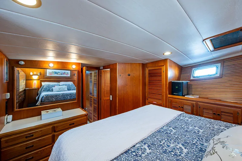Slide: The Image of Luxurious wood-paneled bedroom in 2001 Kadey-Krogen 58 yacht, featuring cozy bedding and ample storage. - 27