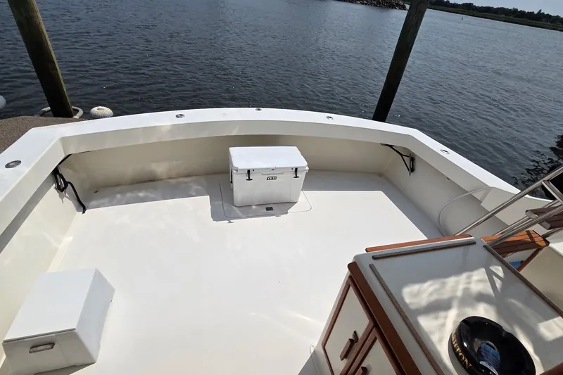 Slide: The Image of 1989 Jersey 42 Convertible Sportfisherman boat deck with cooler, docked by calm waters. - 6