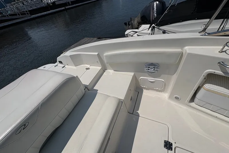 Slide: The Image of 2005 Regal 2600 LSR boat interior with white seating and speaker, docked by the water. - 7