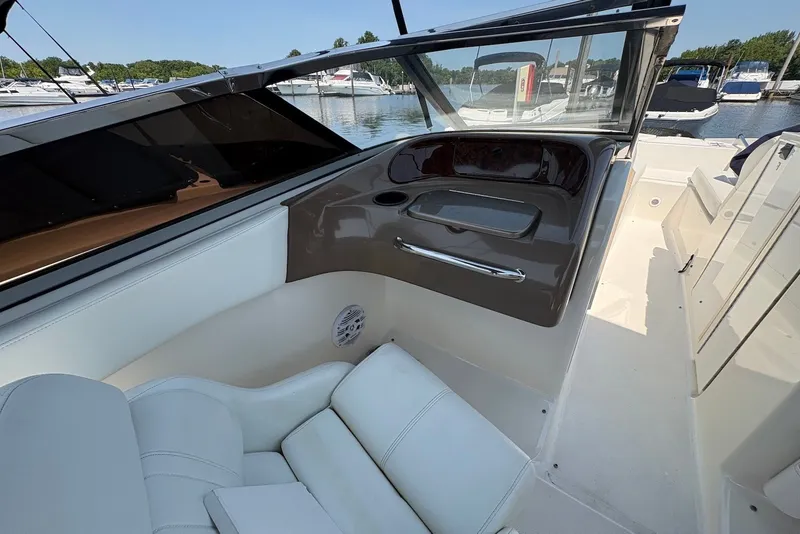 Slide: The Image of 2005 Regal 2600 LSR boat interior with white seating and dashboard, docked at marina. - 11