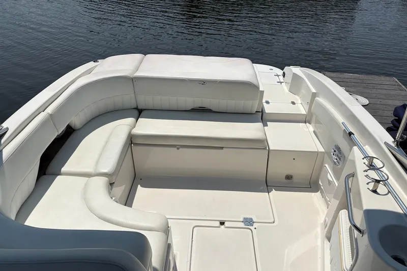 Slide: The Image of 2005 Regal 2600 LSR boat interior with white seating, docked by calm water. - 5
