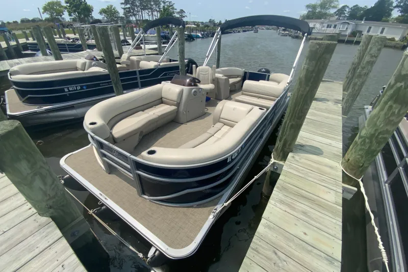 The Image of A 2023 Cypress Cay Seabreeze 232 pontoon boat docked at a wooden pier. It features beige seating. - 0