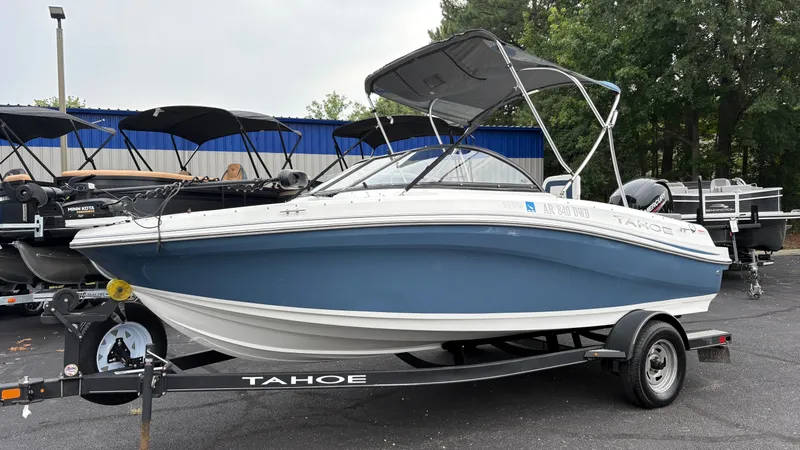 The Image of A blue and white 2022 Tahoe 185 S boat on a trailer in a parking lot. - 1