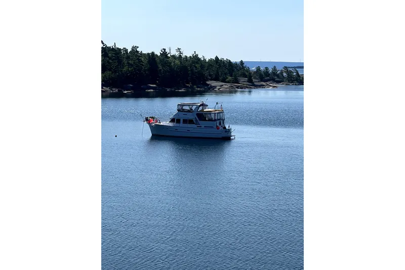 Slide: The Image of A 1985 Jefferson boat anchored on a serene lake with a forested shoreline. - 4
