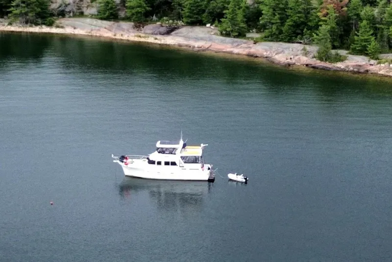 Slide: The Image of A 1985 Jefferson boat anchored in a serene lake with lush green shoreline. - 5