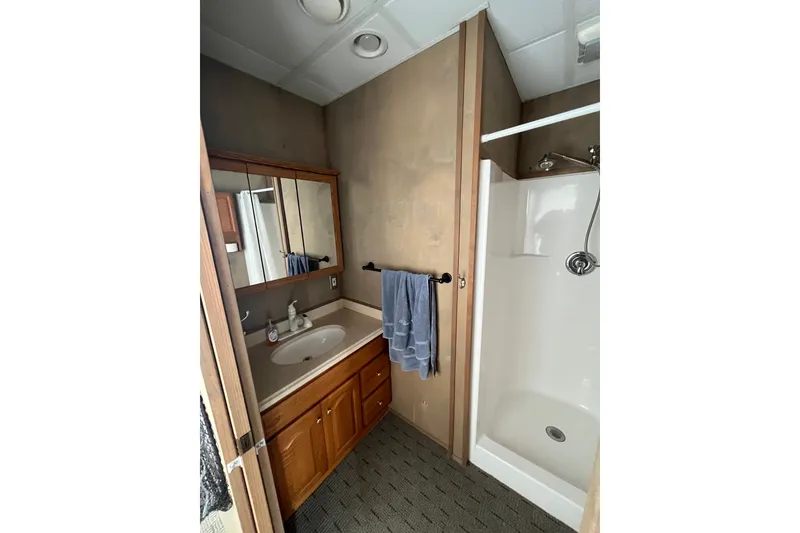 Slide: The Image of Compact bathroom in a 2009 Custom tritoon, featuring a shower and vanity. - 12