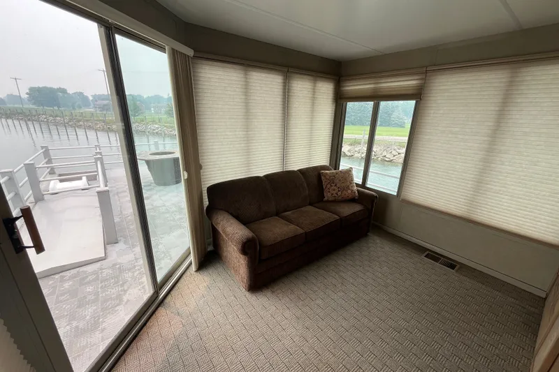 Slide: The Image of Interior of a 2009 custom tritoon with a cozy sofa and large windows overlooking water. - 30
