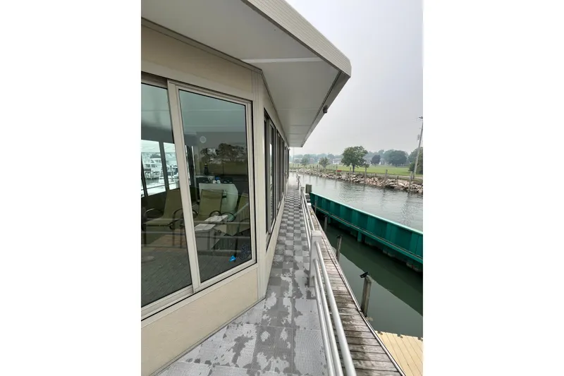 Slide: The Image of Side view of a 2009 custom tritoon boat docked by a serene waterfront. - 24