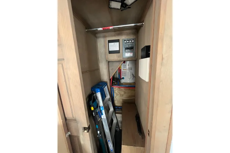 Slide: The Image of Interior storage compartment of a 2009 Custom tritoon, featuring tools and electrical panel. - 10
