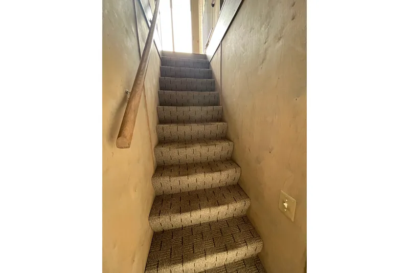 Slide: The Image of Carpeted stairs with wooden handrail in a well-lit interior space. - 19