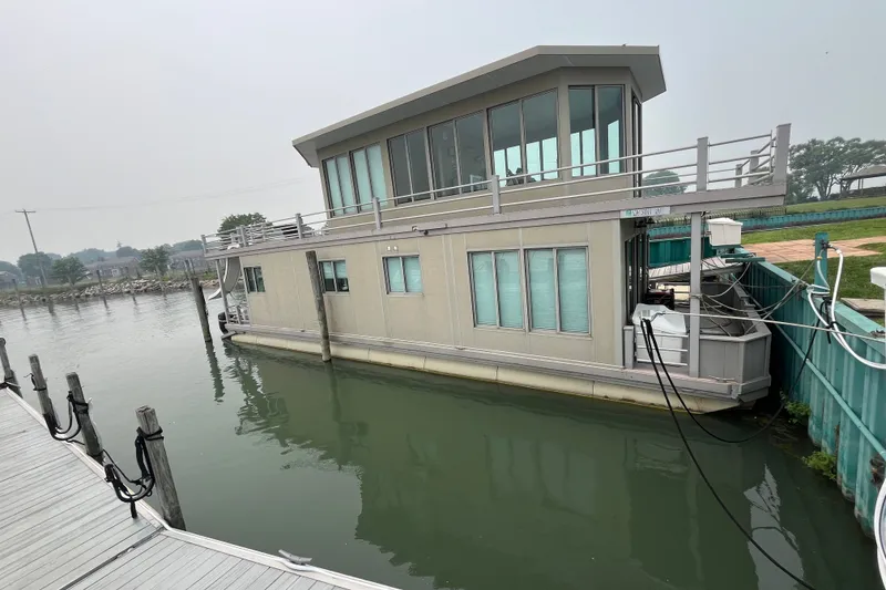Slide: The Image of Custom 2009 tritoon houseboat docked on calm water, featuring large windows and modern design. - 35