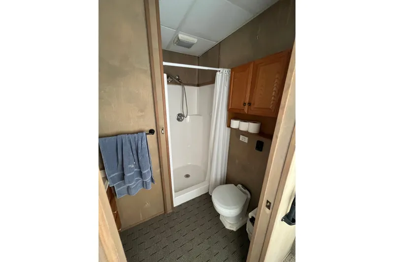 Slide: The Image of Bathroom interior of a 2009 Custom tritoon with shower, toilet, and wooden cabinets. - 11