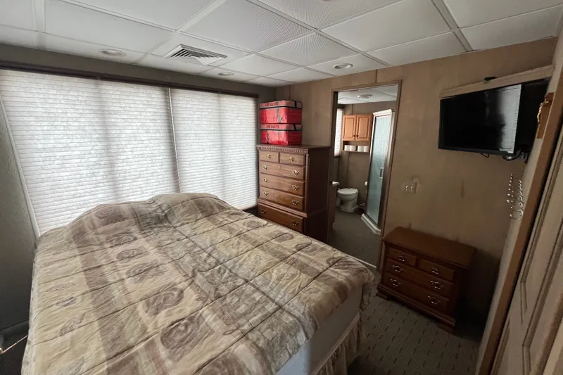 Slide: The Image of Cozy bedroom with patterned bedding, wooden furniture, and a wall-mounted TV in a 2009 custom tritoon. - 14