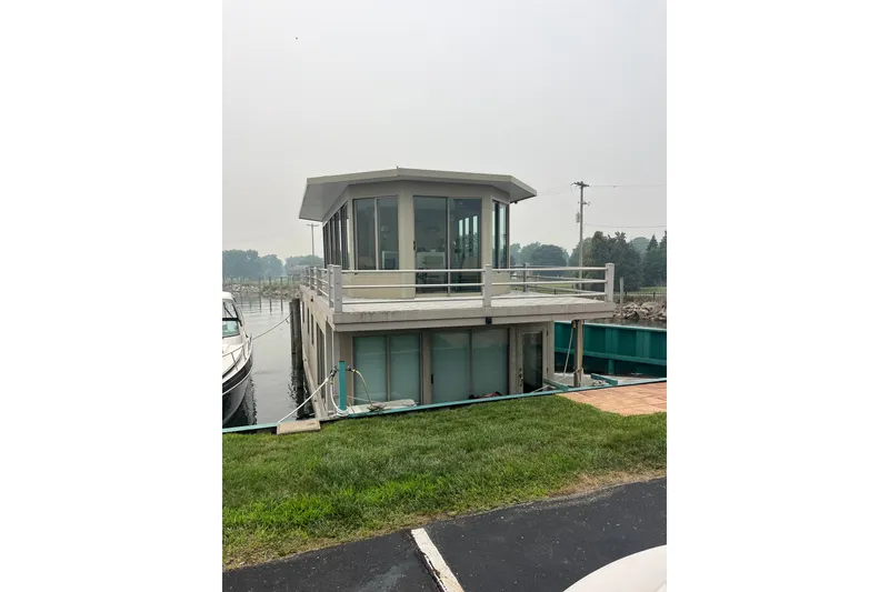 The Image of Custom 2009 tritoon houseboat docked by grassy shore, featuring modern design and large windows. - 1