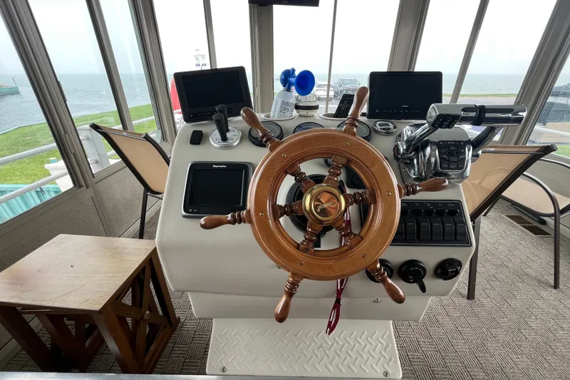 Slide: The Image of Steering wheel and controls of a 2009 custom tritoon boat, overlooking water. - 33