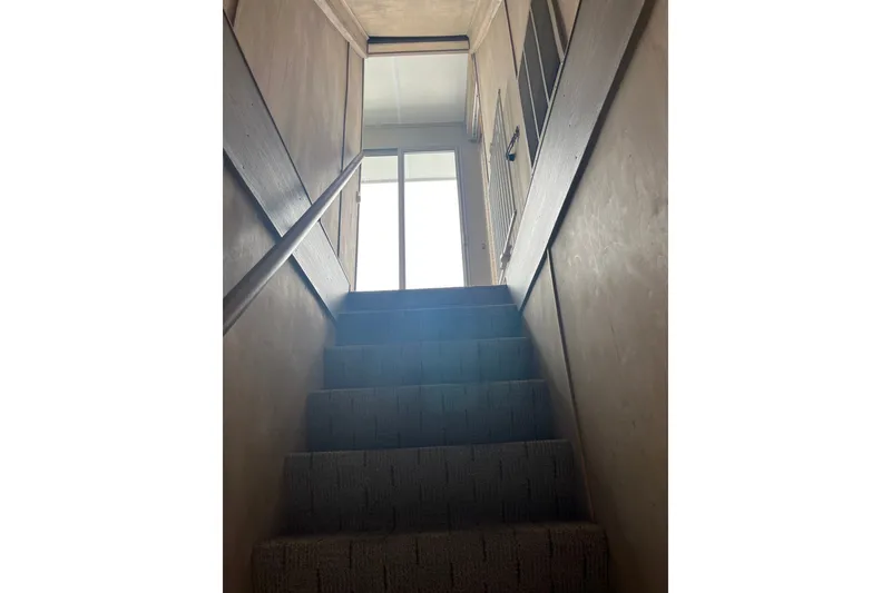 Slide: The Image of Carpeted staircase leading to a bright doorway with wooden railings. - 20