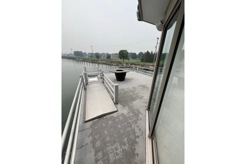 Slide: The Image of 2009 Custom tritoon boat deck with railing, docked near a scenic shoreline. - 26