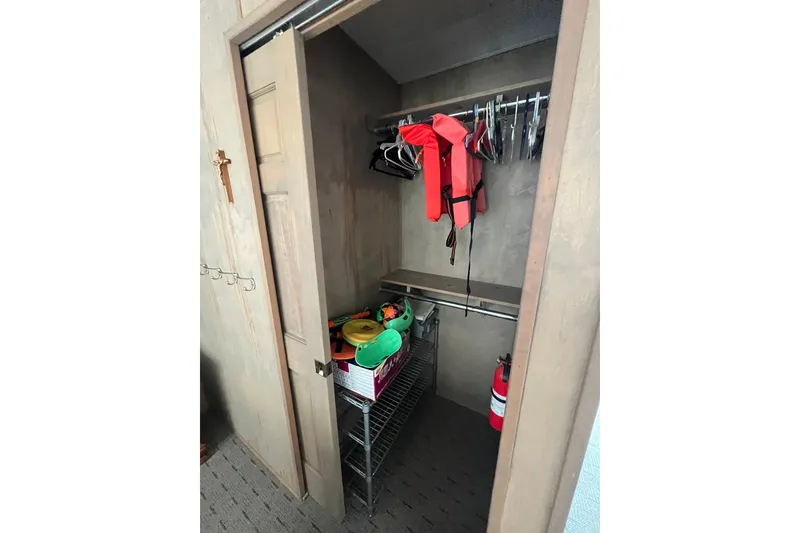 Slide: The Image of Small storage closet with life jackets, hangers, and a fire extinguisher on a shelf. - 15