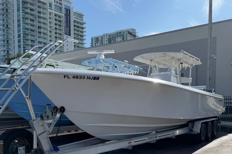 The Image of A 2007 Contender 33 Tournament boat on a trailer, parked in front of modern buildings. - 0