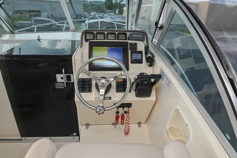 Slide: The Image of 2007 Pursuit OS 285 Offshore boat helm with steering wheel and navigation controls. - 25