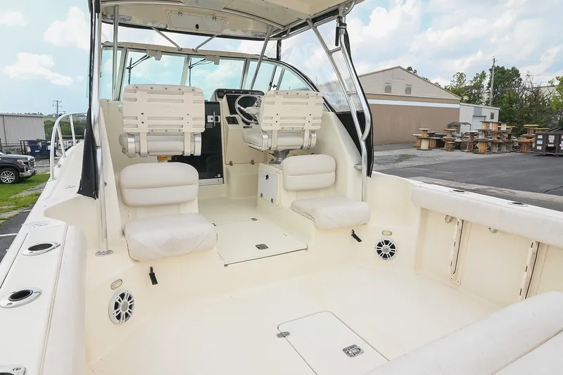 Slide: The Image of 2007 Pursuit OS 285 Offshore boat interior with seating and helm, parked outdoors. - 11