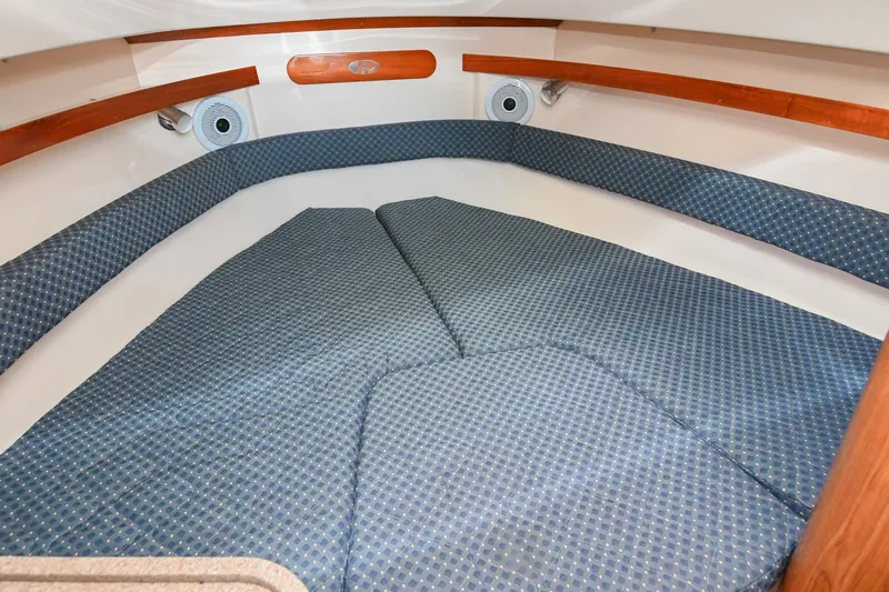 Slide: The Image of 2007 Pursuit OS 285 Offshore cabin interior with blue cushioned seating and wooden accents. - 33