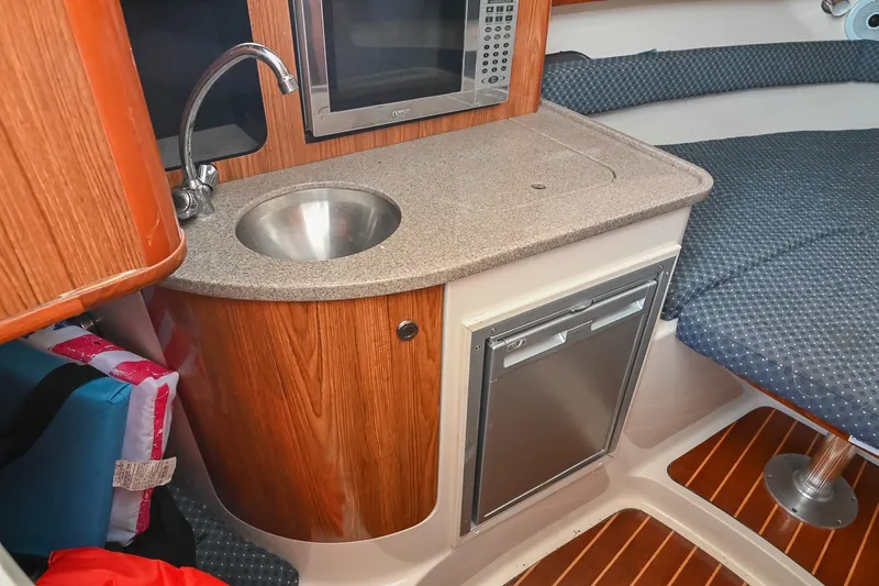 Slide: The Image of 2007 Pursuit OS 285 Offshore cabin with sink, microwave, and compact fridge. - 31