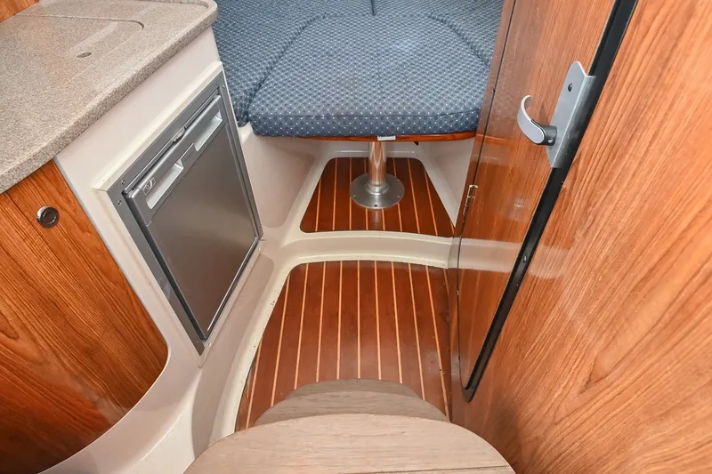 Slide: The Image of 2007 Pursuit OS 285 Offshore cabin interior with wood finish and compact kitchenette. - 32