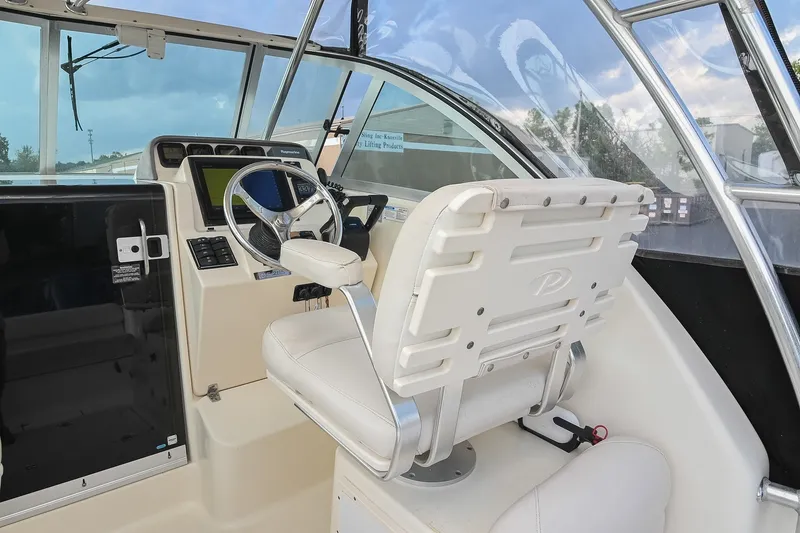 Slide: The Image of 2007 Pursuit OS 285 Offshore boat cockpit with steering wheel and navigation controls. - 24