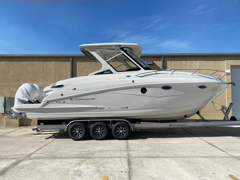 The Image of A 2023 Crownline 310 CRX on a trailer, featuring twin outboard engines and a sleek design. - 1