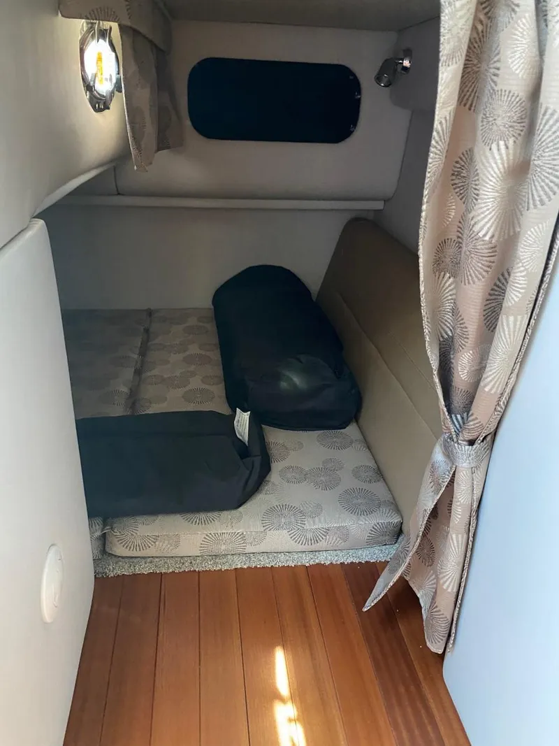 Slide: The Image of Interior of a 2023 Crownline 310 CRX featuring a cozy sleeping area with curtains. - 23