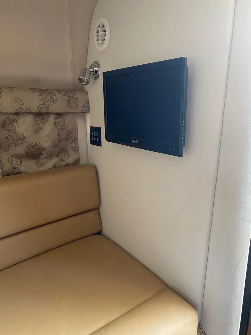 Slide: The Image of Interior of a Crownline 310 CRX with a wall-mounted TV and beige seating. - 26