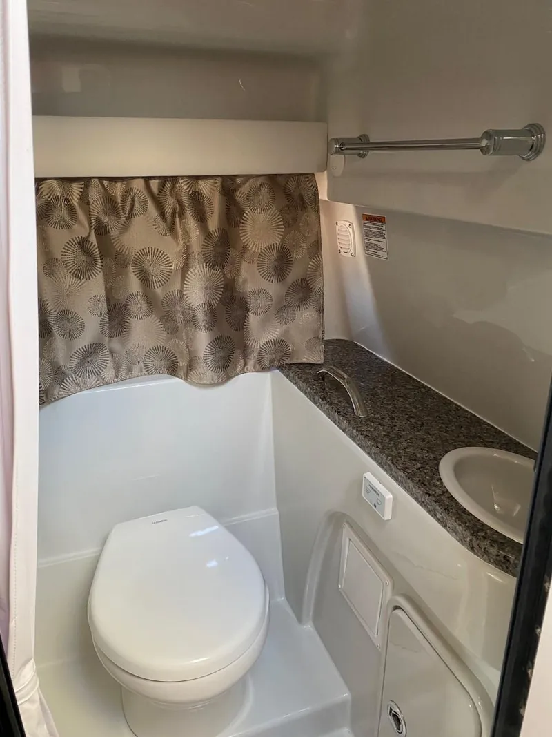Slide: The Image of The image shows a boat bathroom with a toilet, sink, and curtain. - 25