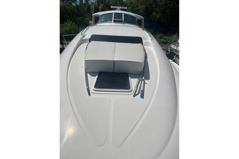 Slide: The Image of 2002 Sea Ray 480 Motor Yacht deck with sunpad and hatch, surrounded by greenery. - 6