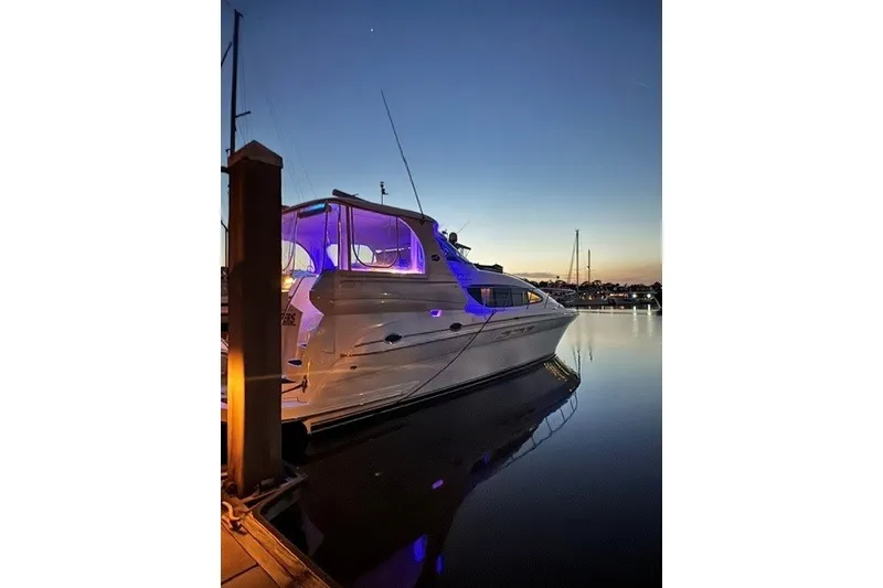 Slide: The Image of 2002 Sea Ray 480 Motor Yacht docked at sunset with blue lights reflecting on water. - 27