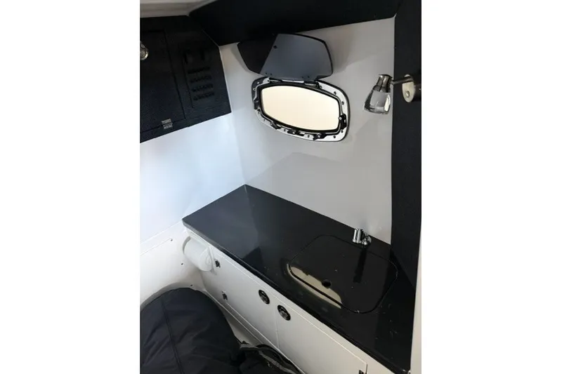 Slide: The Image of Interior of 2027 Monterey Elite 27 SD boat, featuring sleek black countertop and porthole window. - 15