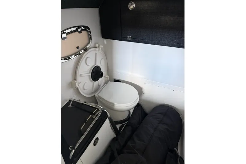 Slide: The Image of Interior of 2027 Monterey Elite 27 SD boat featuring a compact marine toilet. - 16