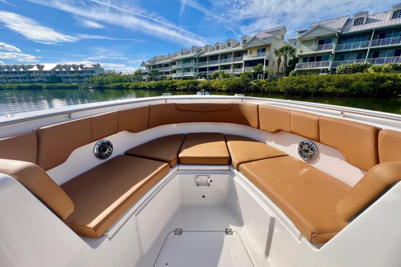 Slide: The Image of 2025 Robalo R302 Center Console boat with tan seating, docked near waterfront homes. - 18