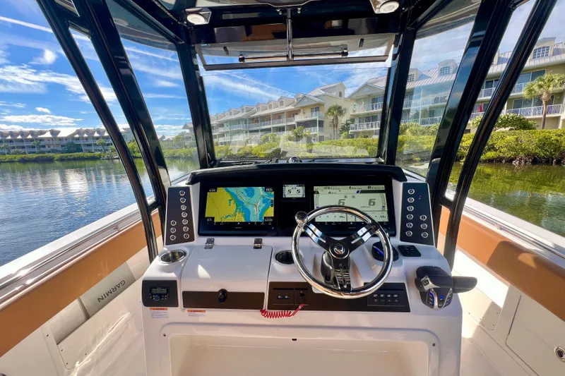 Slide: The Image of 2025 Robalo R302 Center Console boat dashboard with navigation screens and steering wheel. - 2